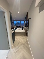 A modern bedroom with a bed, bedside tables, and a view of the city through large windows.