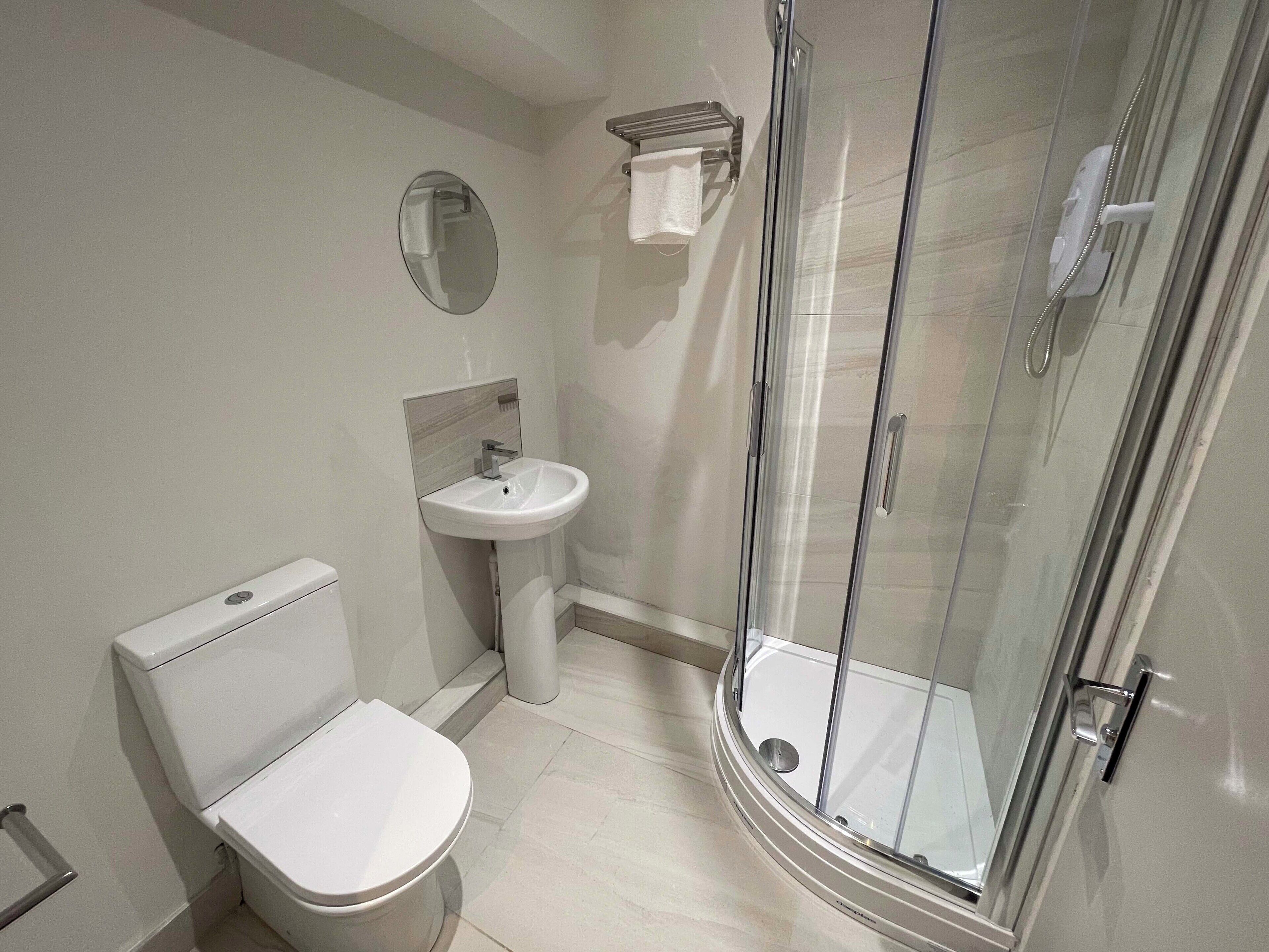 A modern bathroom with a toilet, sink, and glass shower enclosure.