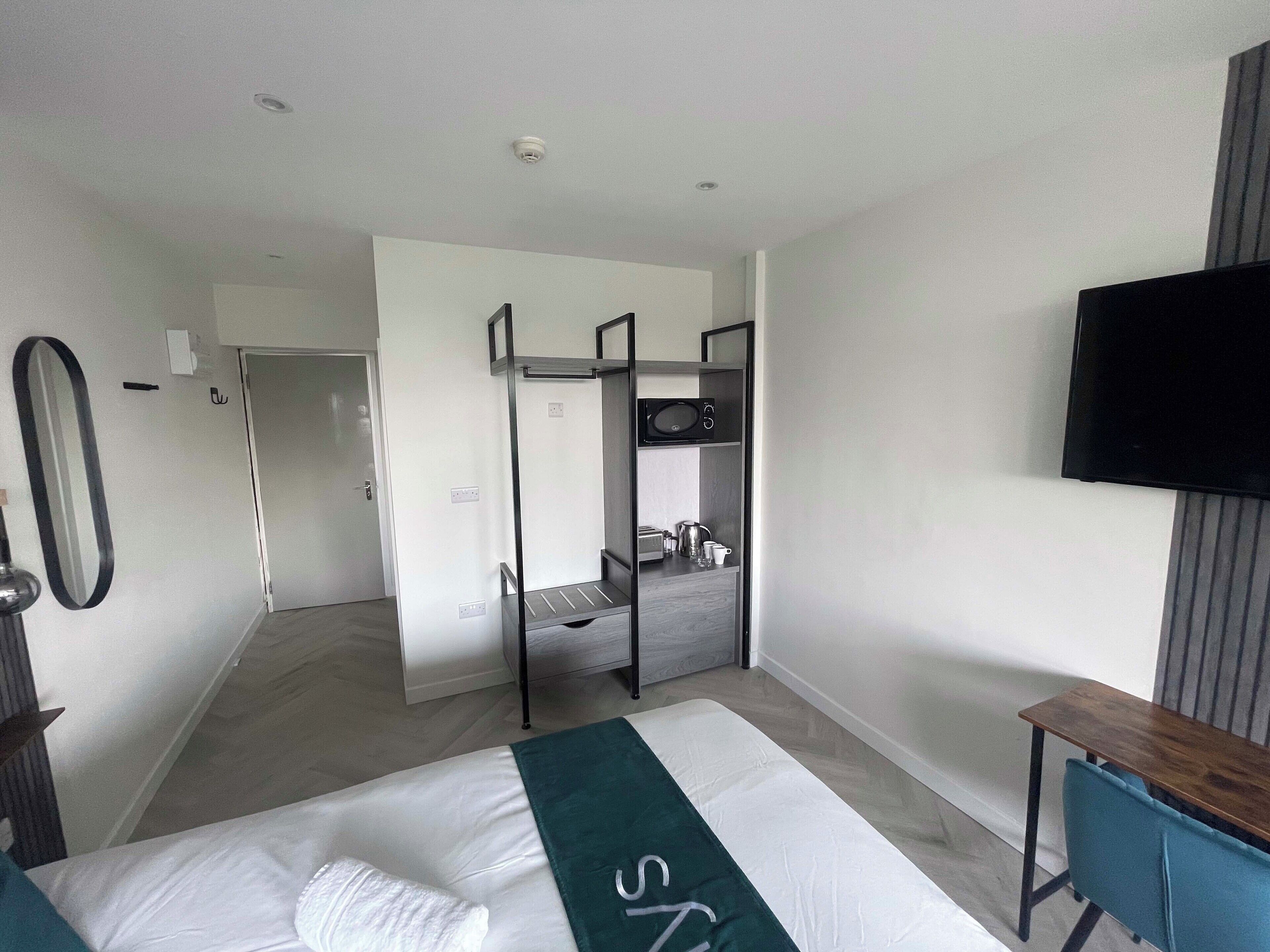 A modern hotel room with a bunk bed, a desk, a flat-screen TV, and a large mirror.