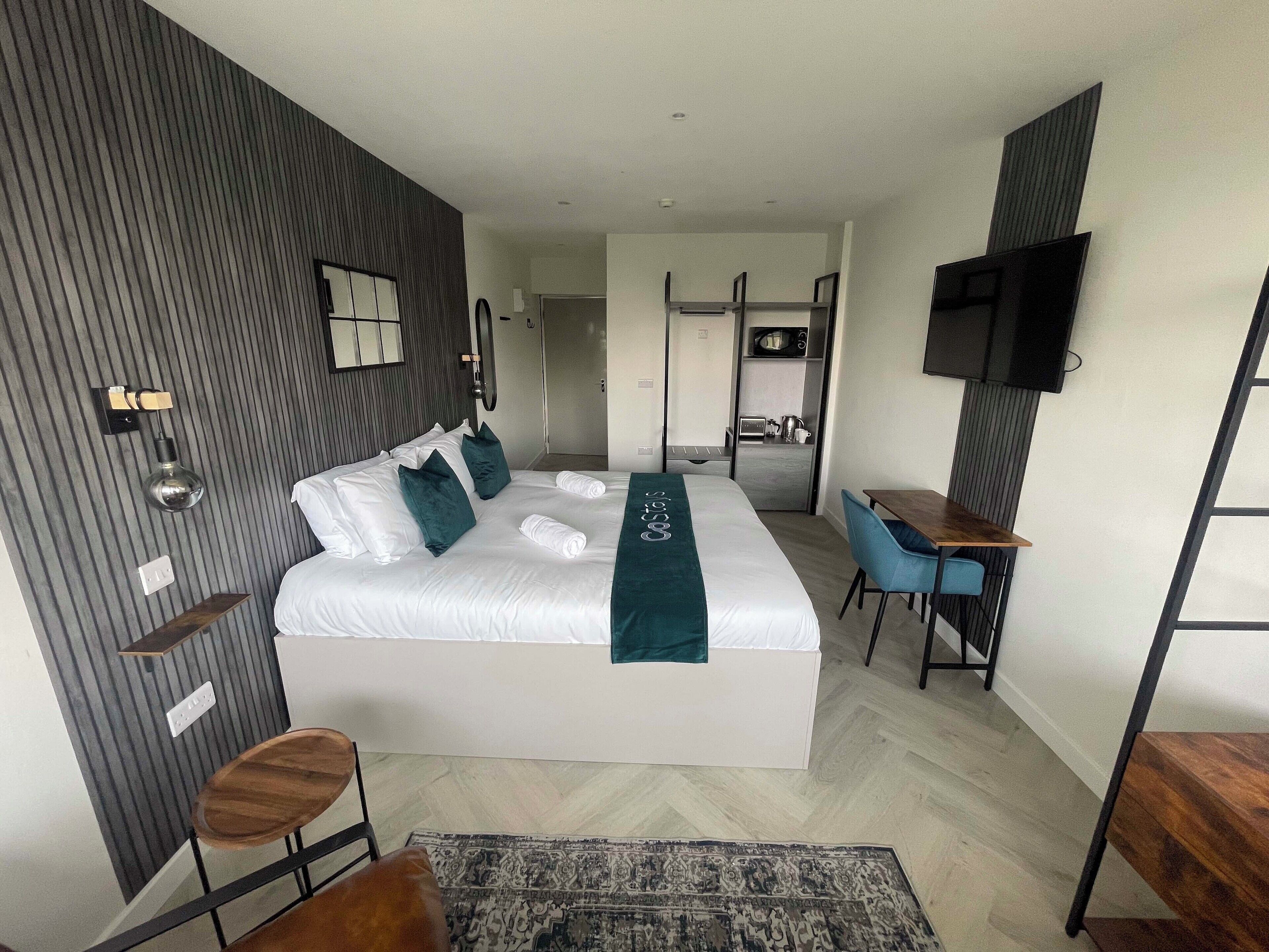 Una habitación de hotel moderna con una cama grande, un escritorio y un televisor.