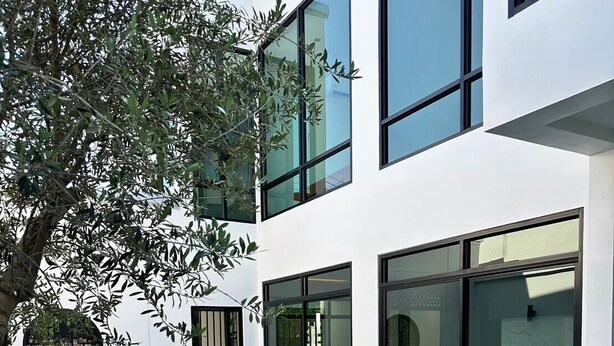Un edificio moderno con piscina, ampie finestre e un albero.