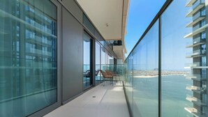 Un balcon moderne aux parois en verre, offrant une vue sur le paysage urbain de la côte.