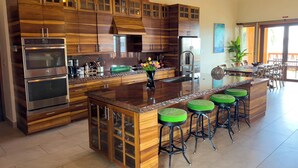 A modern kitchen with wooden cabinetry, stainless steel appliances, and a central island with bar stools.
