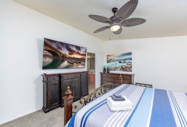 Une chambre à coucher comprenant un lit, un ventilateur de plafond, deux tableaux, une commode et un placard.