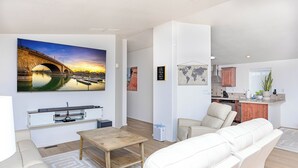 A modern living room with a sofa, a coffee table, and a TV displaying a sunset bridge.