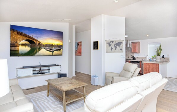 Un salon moderne avec un canapé, une table basse et un téléviseur diffusant une image d’un pont au coucher du soleil.