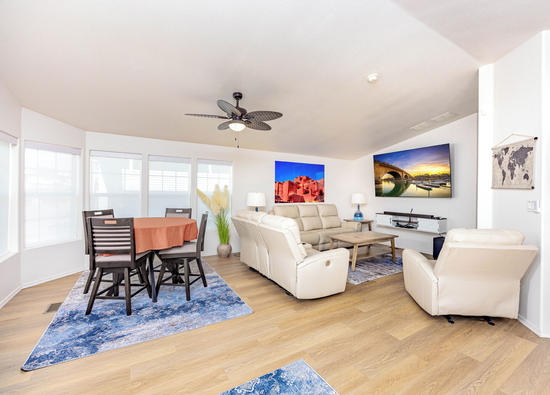 A modern living room with a dining area, white furniture, and large windows.