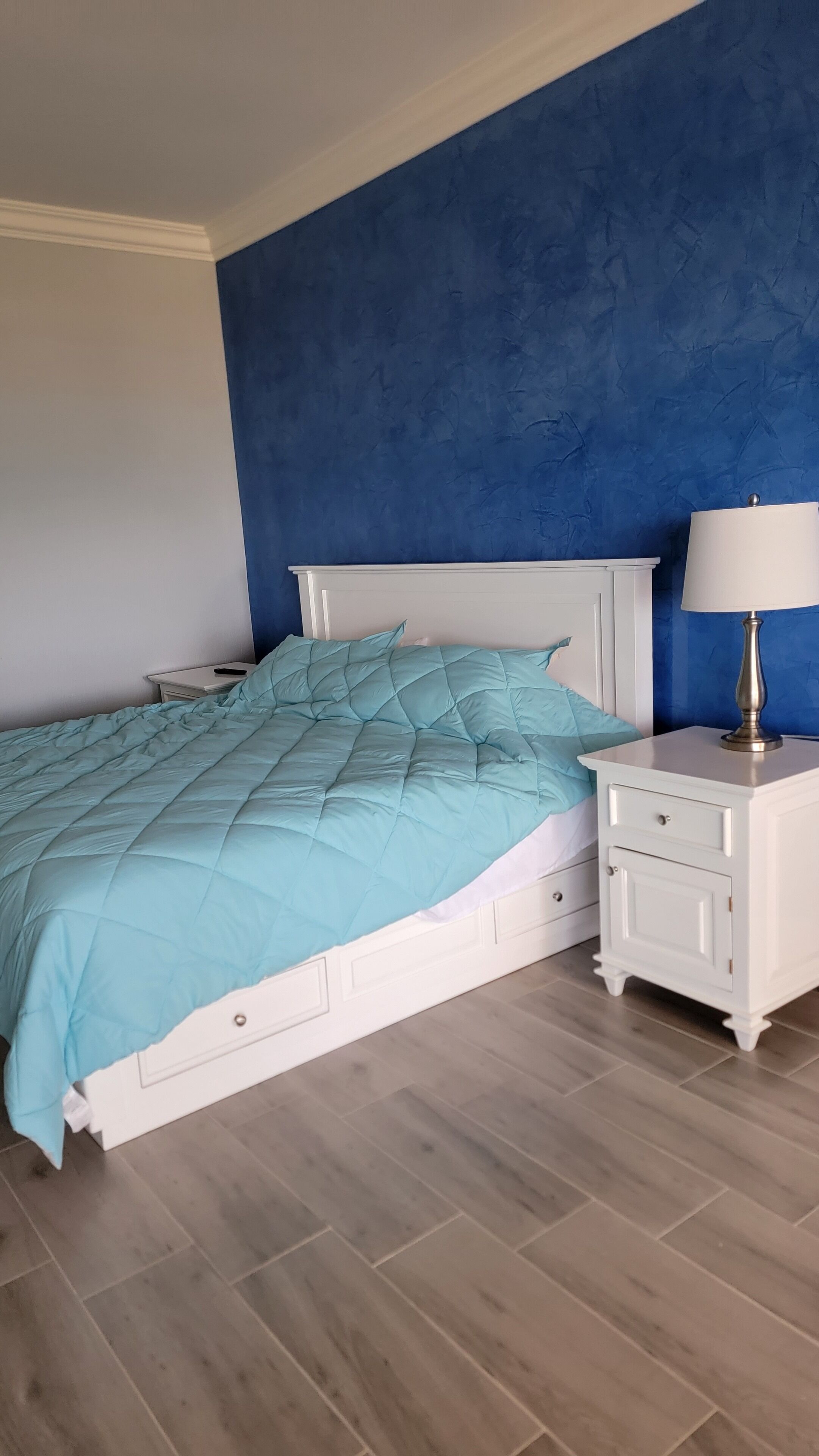 A bedroom with a bed, nightstands, and a lamp.