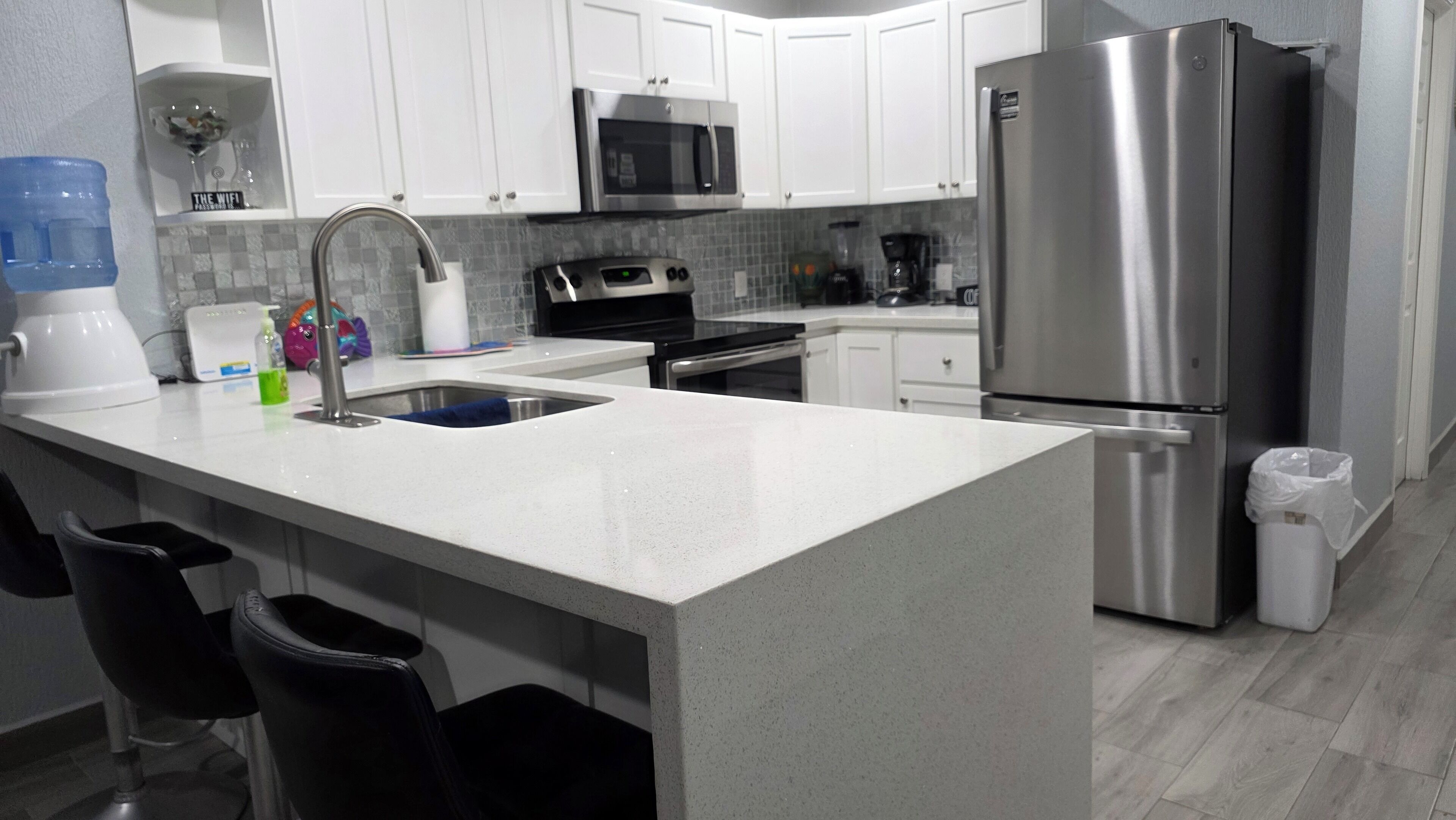 A modern kitchen with white cabinets, stainless steel appliances, and a granite countertop.