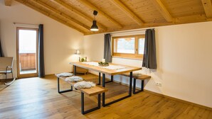 A wooden dining table with benches, a window with curtains, and a ceiling with exposed beams. - 90-square-meter vacation rental for 2 to 6 people (Staudach-Egerndach)