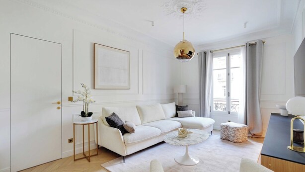 A modern living room with a white sofa, a round coffee table, and a pendant light. - Elegant A/C Apt 2BR/6P – Paris 17th/Monceau (Paris)