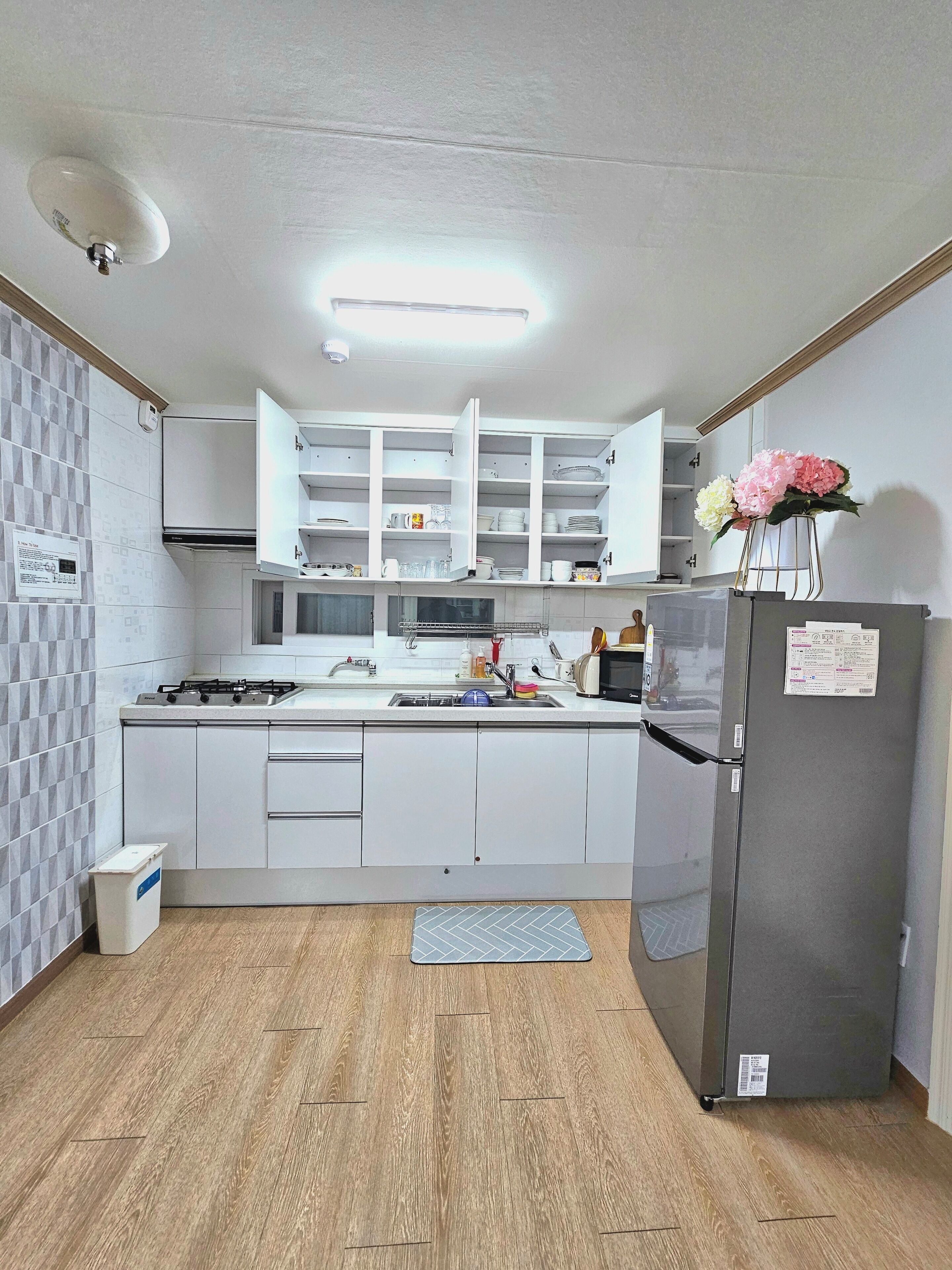 A modern kitchen with white cabinets, a built-in microwave, a gas stove, and a refrigerator.