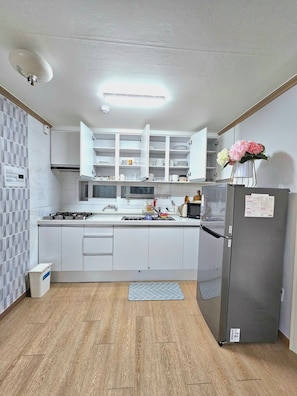 A modern kitchen with white cabinets, a built-in microwave, a gas stove, and a refrigerator.