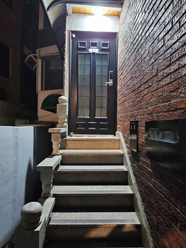 A staircase leading to a dark wooden door with a sign above it.