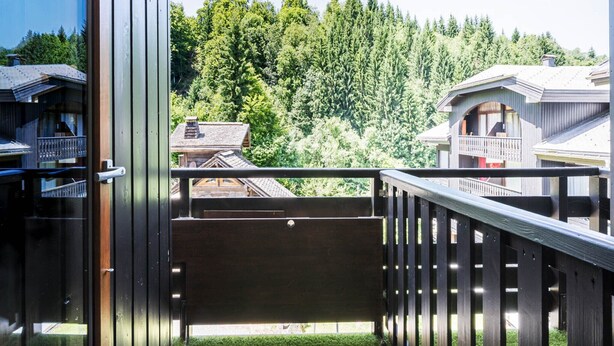 A balcony with a view of a forested hillside.