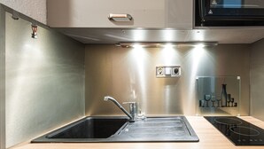 A modern kitchen with a stainless steel sink, a built-in oven, and a wooden countertop.