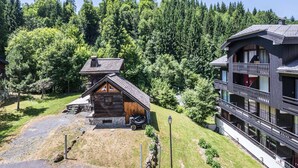 A lodge with a log cabin and a multi-story building, surrounded by dense forest.