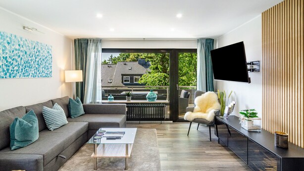 Una sala de estar moderna con un sofá, una mesa de centro, televisor y vistas amplias por un gran ventanal.