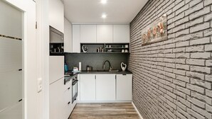 Una cocina moderna con armarios blancos, encimera negra y pared de ladrillo.