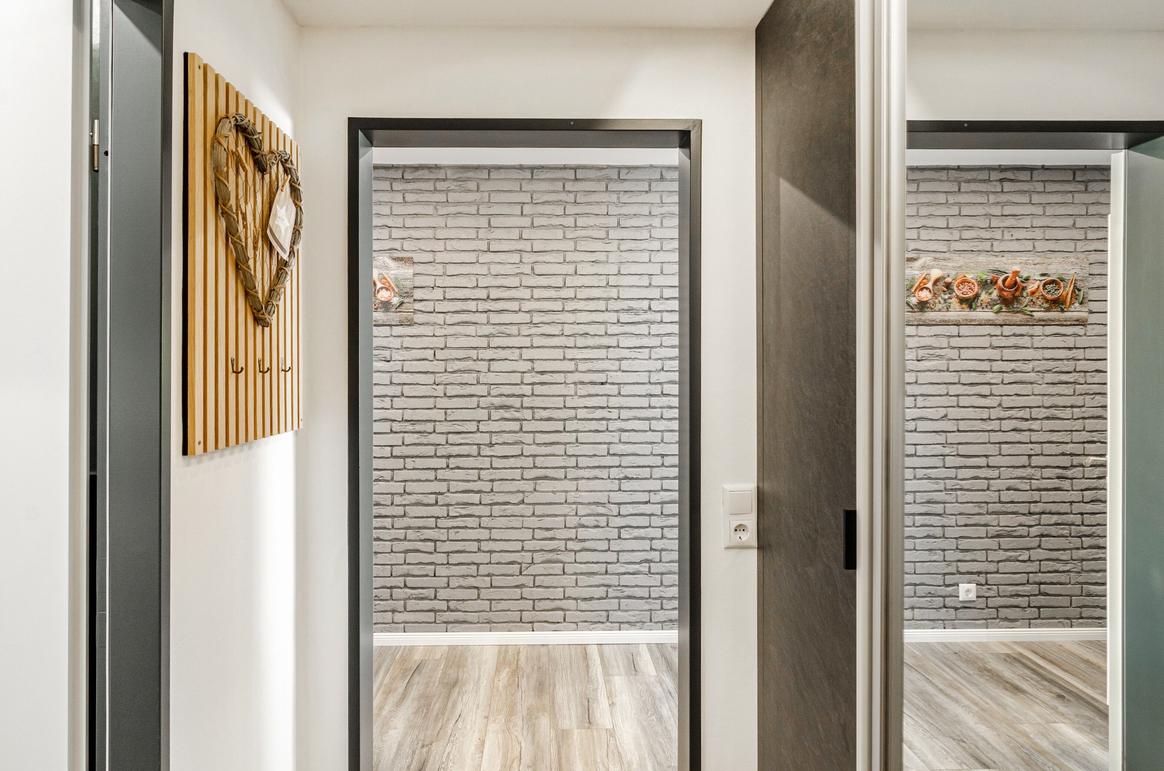 Un couloir avec un lambris en bois, un mur décoré d’un motif en briques et un plancher en bois.