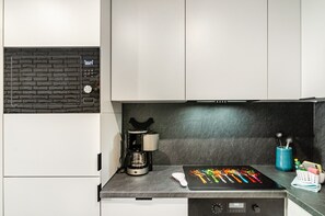 Eine moderne Küche mit Kaffeemaschine, digitaler Uhr und Tablet, das farbenfrohe Grafiken zeigt.