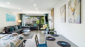 Una habitación de hotel moderna con cama, sofá, mesa de comedor y obras de arte.