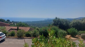 Ein Wohngebiet mit Blick auf das Meer, ein Auto und ein Haus mit Ziegeldach.