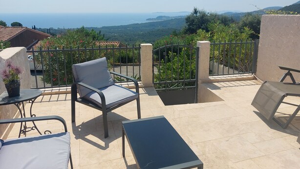 Eine Terrasse mit Stuhl und Tisch, Blick auf das Meer und ein Tor.