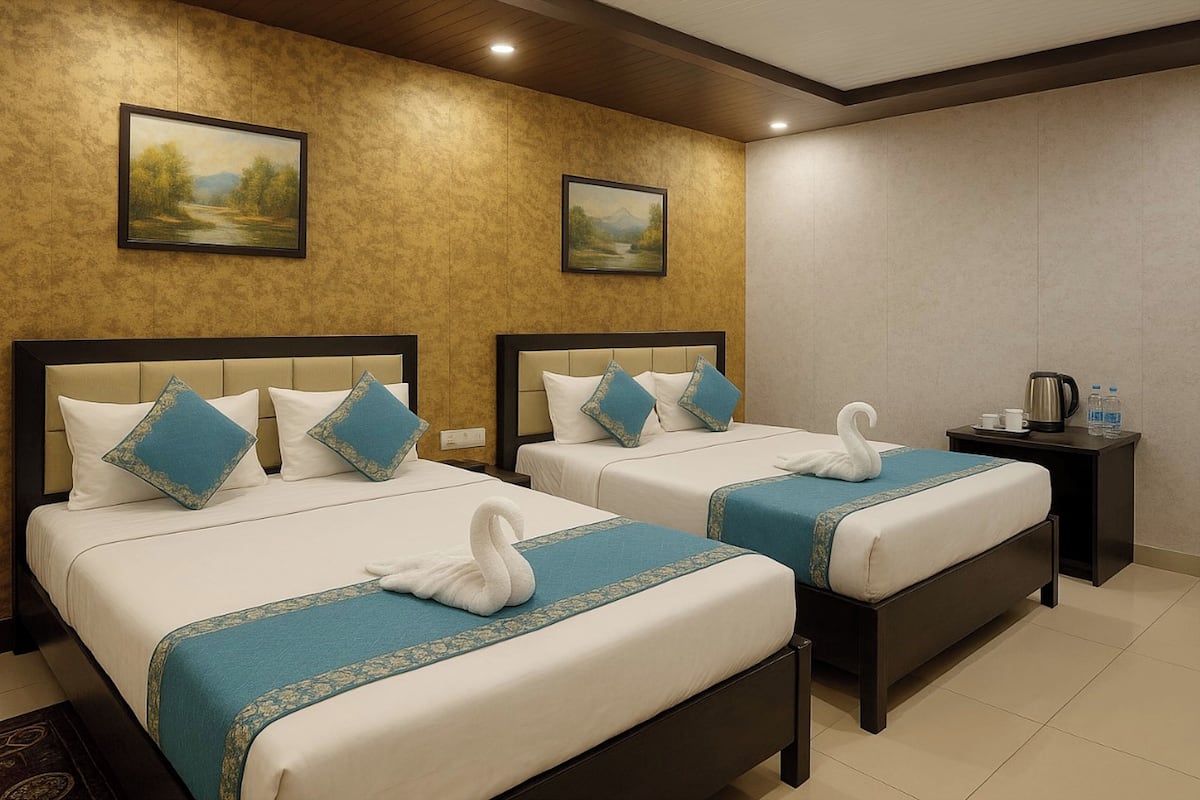 Quarto de hotel com duas camas, cada uma com uma colcha azul e branca, e uma toalha em forma de cisne. Há duas pinturas na parede, uma pequena mesa com chaleira e chávenas, e uma mesa de cabeceira com candeeiro.