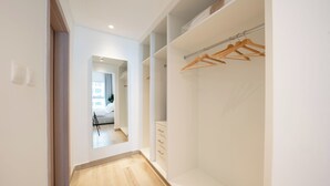 Ein begehbarer Kleiderschrank mit Holzaufhänger, einem Spiegel und einem hellen Boden.