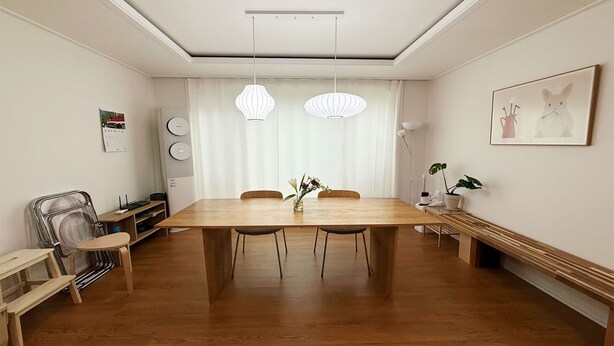 A dining area with a wooden table, chairs, pendant lights, and a bench.