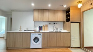 A modern kitchen with wooden cabinets, a built-in washing machine, a sink, and a refrigerator.