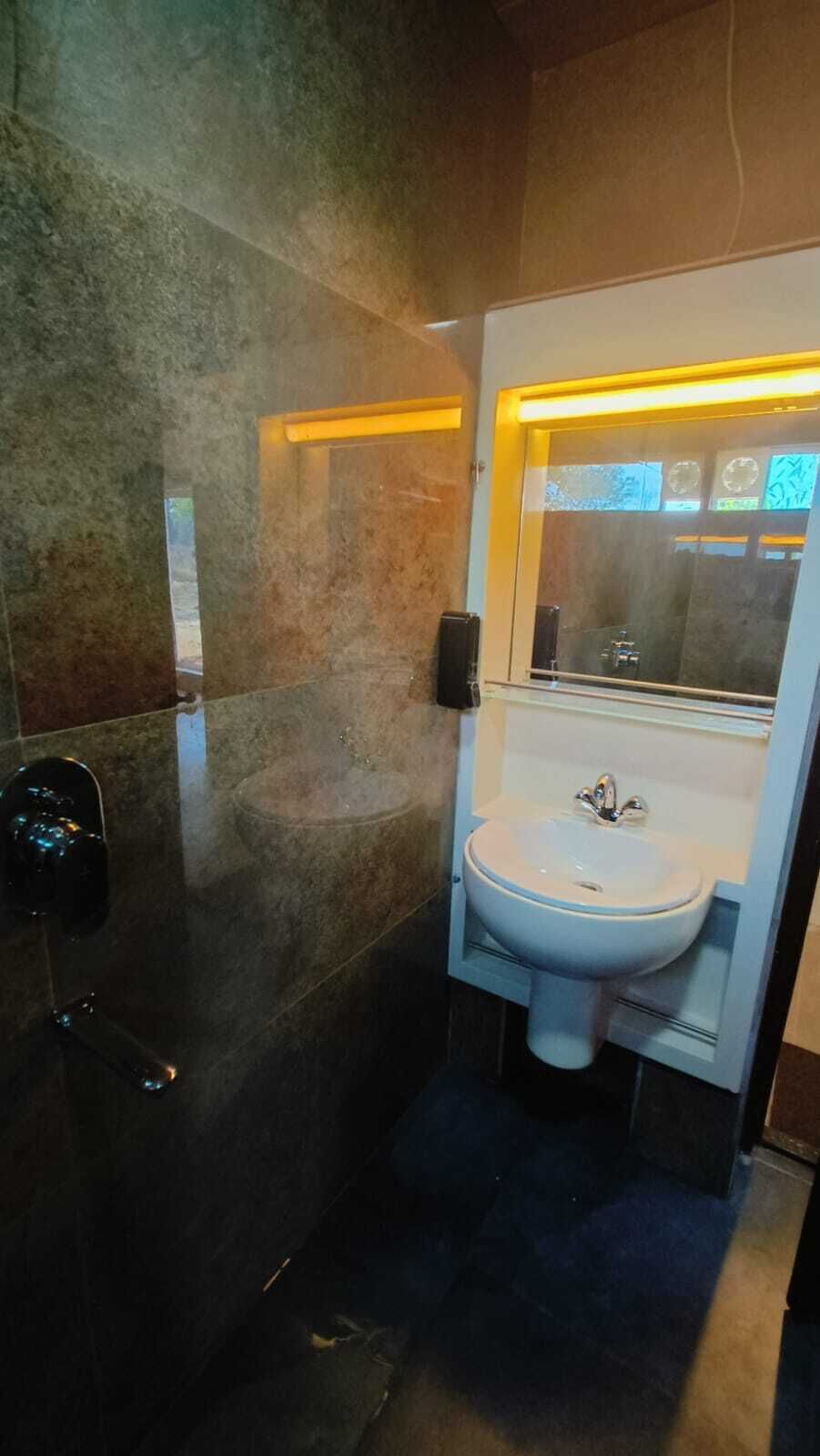 Ein modernes Badezimmer mit einem weißen Waschbecken, einem Spiegel und einem Seifenspender an der Wand.
