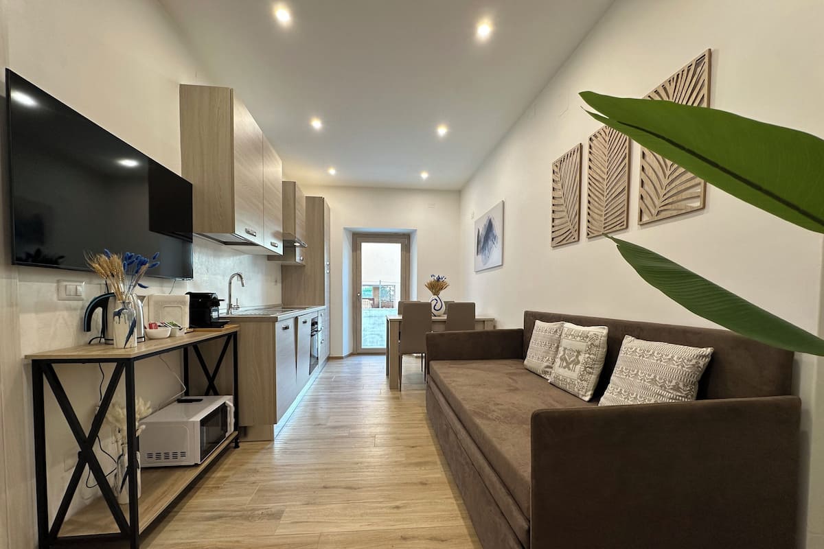 A modern living room with a sofa, TV, kitchen area, and decorative wall art.