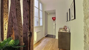 Un couloir avec un plancher en bois, un radiateur, une armoire sombre et un ballon rouge en forme de cœur.
