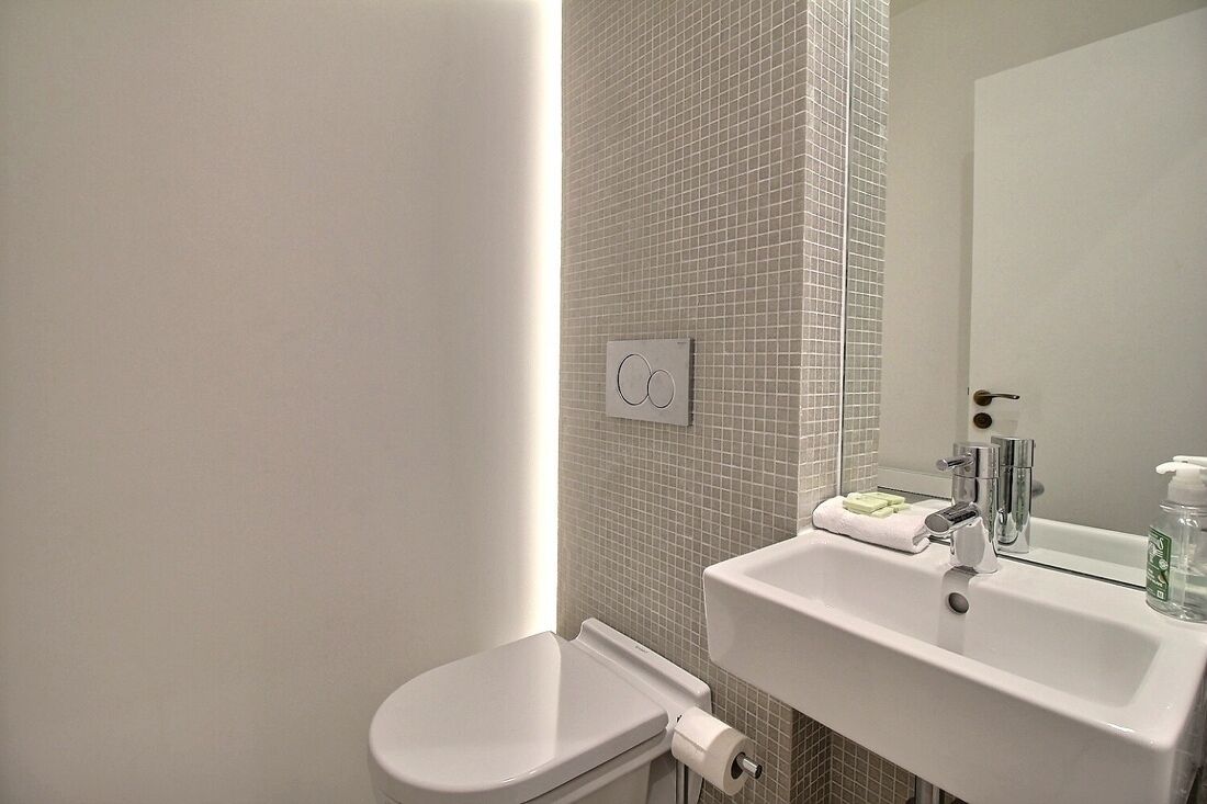 A bathroom with a toilet, sink, and mirror.