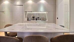 Une cuisine moderne dotée d’un plan de travail en marbre, d’un éclairage encastré et d’un four intégré.