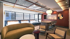 A modern hotel room with a large sofa, a round coffee table, and a dining area with chairs and a table. - illi Jam Shinsaibashi (Osaka)