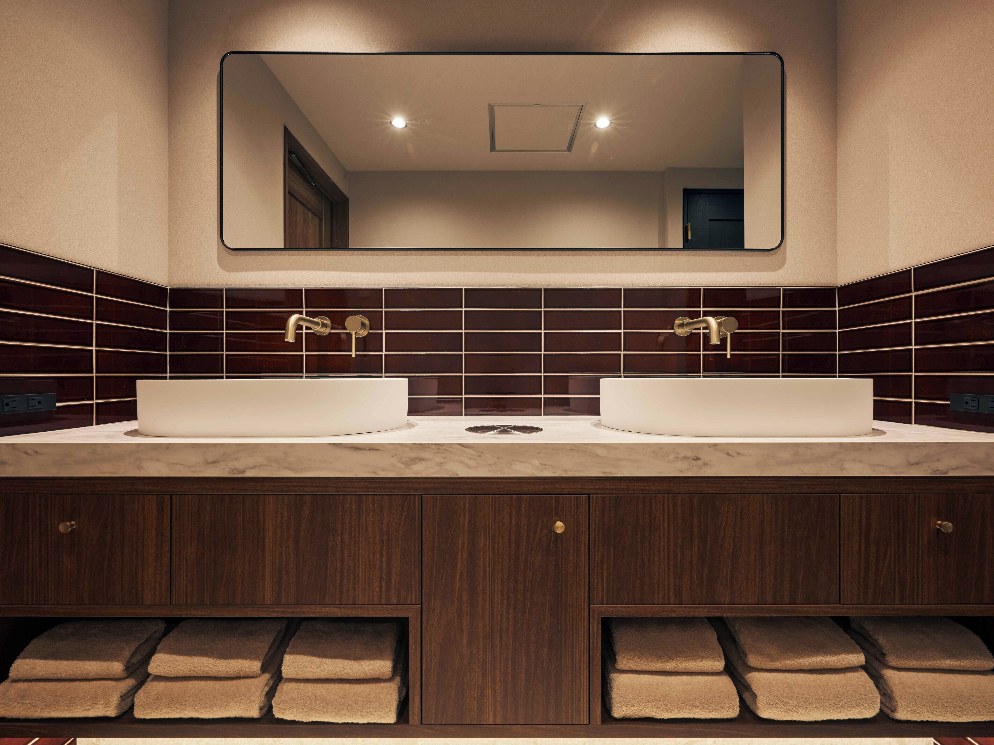 A modern bathroom with two sinks, dark wood cabinetry, and a large mirror above the vanity.