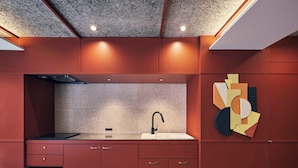 A modern kitchen with a built-in microwave, a sink, and a geometric wall art piece. - illi Jam Shinsaibashi (Osaka)