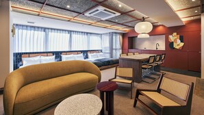 A modern hotel room with a sofa, dining table, chairs, and a kitchen area. - illi Jam Shinsaibashi (Osaka)