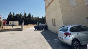 A parking lot with a building, a parked car, and a clear sky. - Apartment close to the beach with a view! (Port-de-Bouc)
