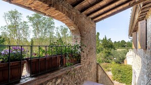 A balcony with stone walls, a wooden floor, and a metal railing.