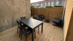 An outdoor patio with a wooden deck, a table with chairs, and a wooden fence.