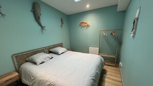 A bedroom with a bed, a bedside table, a window, and a wall-mounted dreamcatcher.
