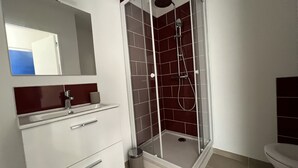 A modern bathroom with a glass-enclosed shower, a white vanity with drawers, and a toilet.