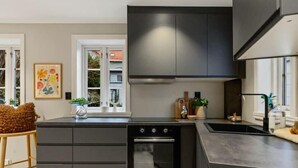 A modern kitchen with dark cabinetry, a built-in oven, and a large island with a sink.