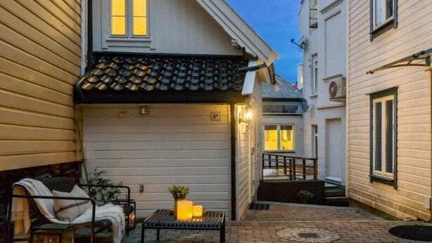 A cozy outdoor seating area with a bench and a table, a small potted plant, and a lantern.