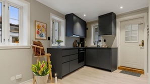 A modern kitchen with dark cabinetry, a central island, and a dining area with a vase of flowers and a candle.