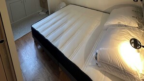 Un dormitorio con cama, espejo, ventana y lavamanos.